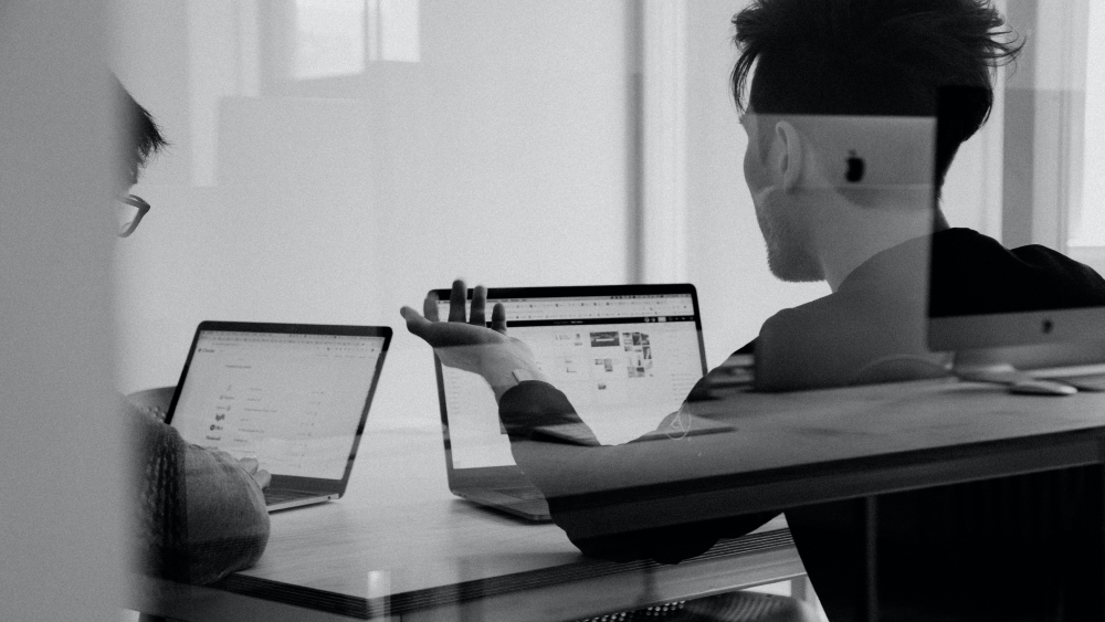 Photo en noir et blanc. Un homme est sur son son ordinateur portable. 